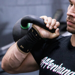 Picsil Schweissband am Handgelenk mit einer Kettlebell im Hintergrund.