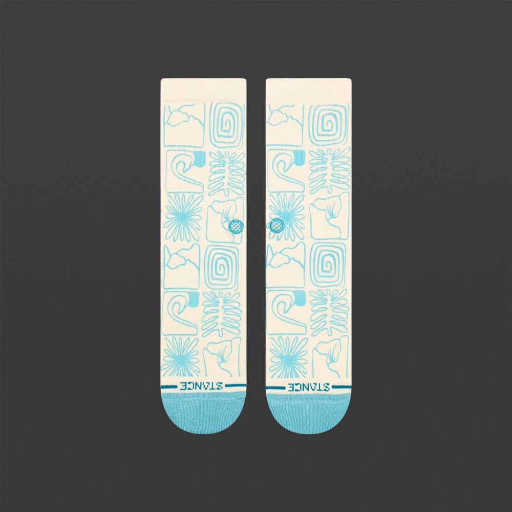 Ein Paar cremefarbene Stance Socken mit hellblauem Muster aus grafischen Formen, Wellen und Blumen liegt flach auf dunklem Hintergrund.