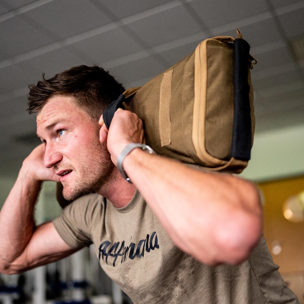 Athlet beim Hyrox-Training mit Affenhand® Sandsack auf der Schulter – voller Fokus und Power.