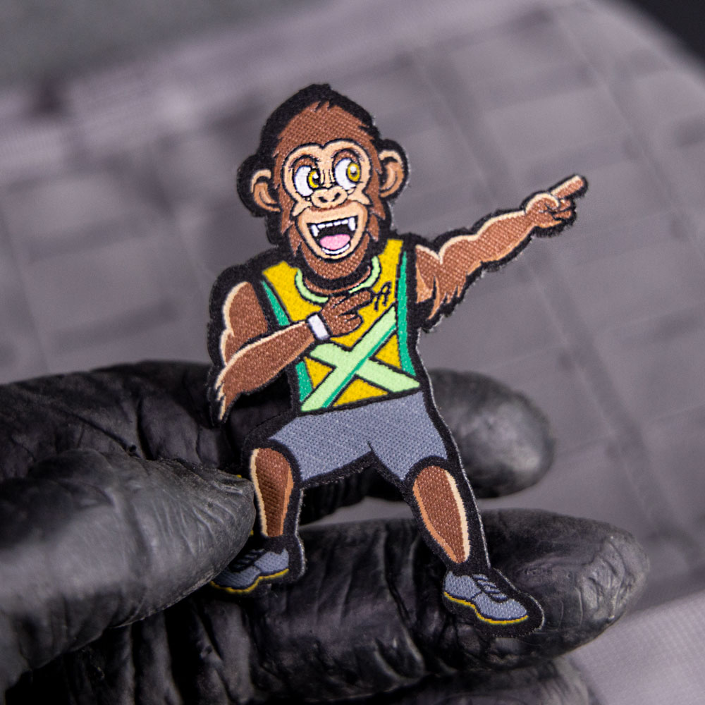 Hand hält einen Klett-Patch, auf dem ein rennender Gorilla dargestellt ist.