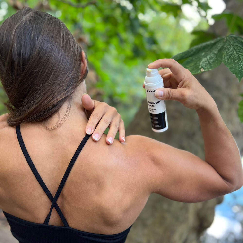 Athletin Natalie verwendet Recovery Balsam von Blackroll am Nacken