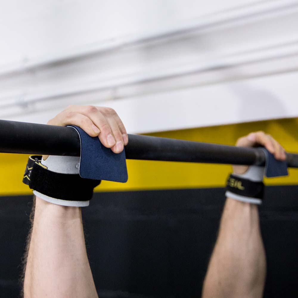Weiß-blaue Picsil Condor Grips liegen auf dem Boden eines Fitness-Studios.